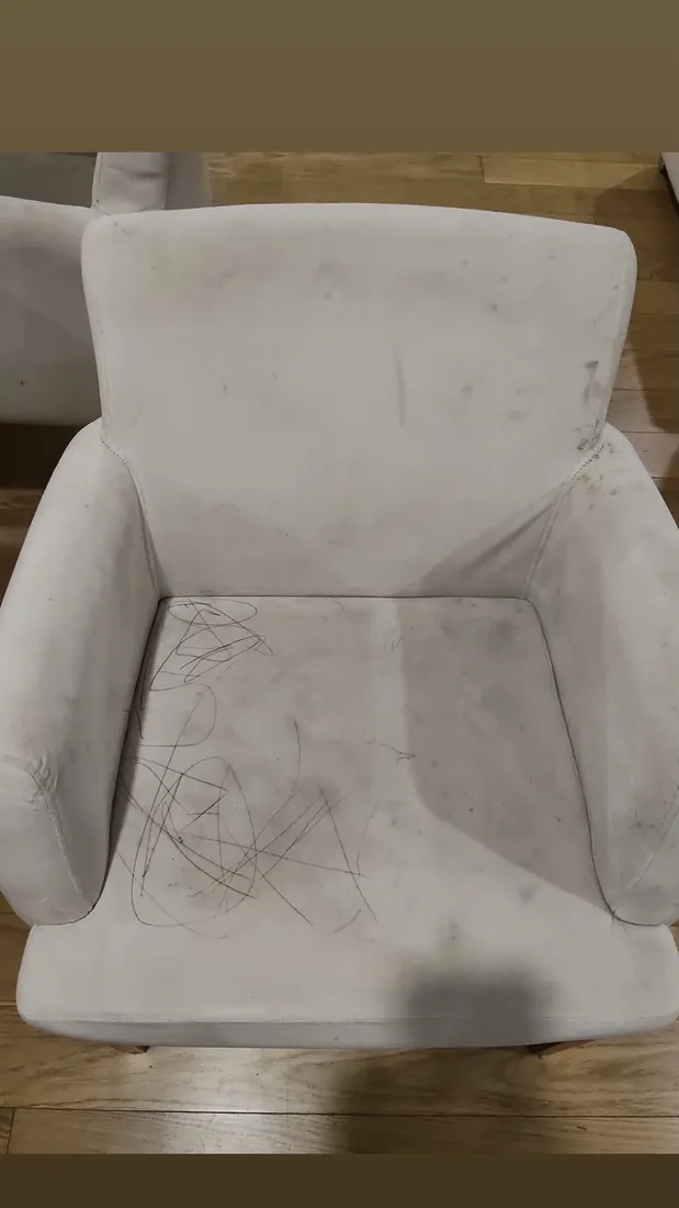 Cadeira estofada clara com manchas e riscos de caneta, antes da limpeza