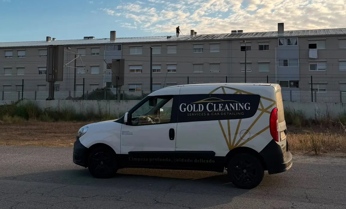 Carrinha da Gold Cleaning e um profissional a limpar o telhado de um edifício ao fundo